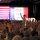 A crowd raises their hands in support during a political rally, with flags in the background — Democrats governor majority