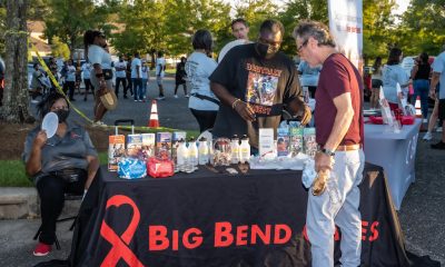 A community event table displaying HIV prevention materials and resources, with people engag — HIV prevention funding cuts