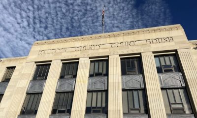 Facade of a county courthouse with a flag and blue sky in the background, — District Attorney Elections Prison Admissions