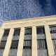Facade of a county courthouse with a flag and blue sky in the background, — District Attorney Elections Prison Admissions