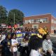NC A&T campus polling site march with students carrying voter signs and university mascots on a sunny street