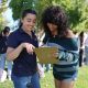 Two young women discussing and reviewing a clipboard outdoors, surrounded by a group of p — Gen Z abortion ballot measures
