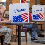 Voters cast ballots at privacy booths marked “I Voted,” illustrating Ballot Measure Reading Level concerns.