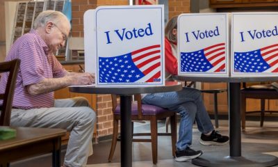 Voters cast ballots at privacy booths marked “I Voted,” illustrating Ballot Measure Reading Level concerns.