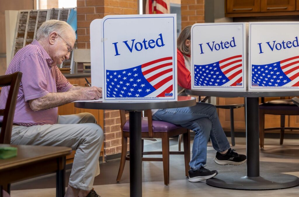 Voters cast ballots at privacy booths marked “I Voted,” illustrating Ballot Measure Reading Level concerns.