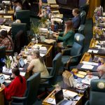 Women Running for State Legislature represented among lawmakers seated at desks in a legislative chamber