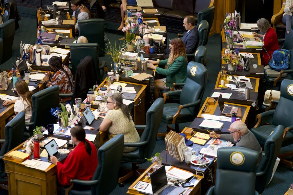 Women Running for State Legislature represented among lawmakers seated at desks in a legislative chamber