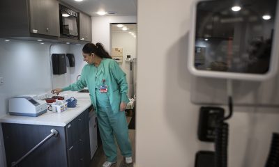 Healthcare worker in teal scrubs handles supplies in a clinical room, illustrating the rising uninsured rate in US.