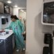 Healthcare worker in teal scrubs handles supplies in a clinical room, illustrating the rising uninsured rate in US.