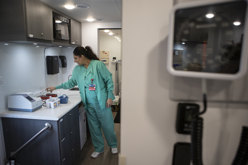 Healthcare worker in teal scrubs handles supplies in a clinical room, illustrating the rising uninsured rate in US.