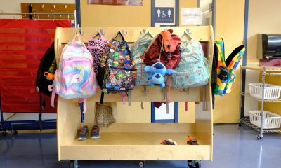 Colorful backpacks hanging on a wooden rack in a school hallway, representing educa — Education Freedom Tax Credit program