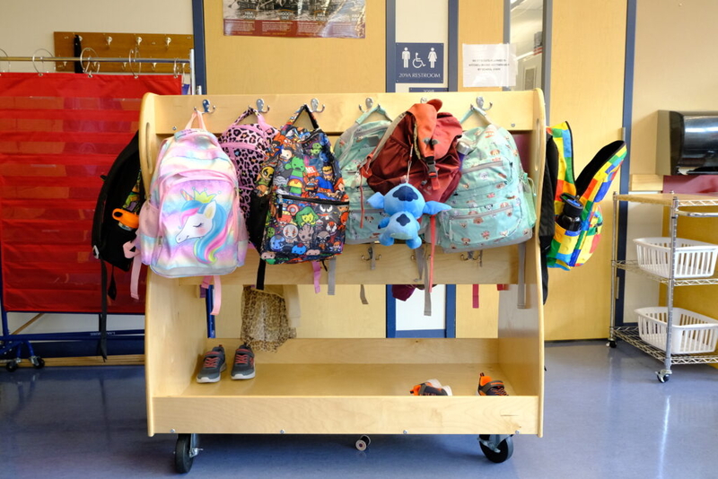 Colorful backpacks hanging on a wooden rack in a school hallway, representing educa — Education Freedom Tax Credit program