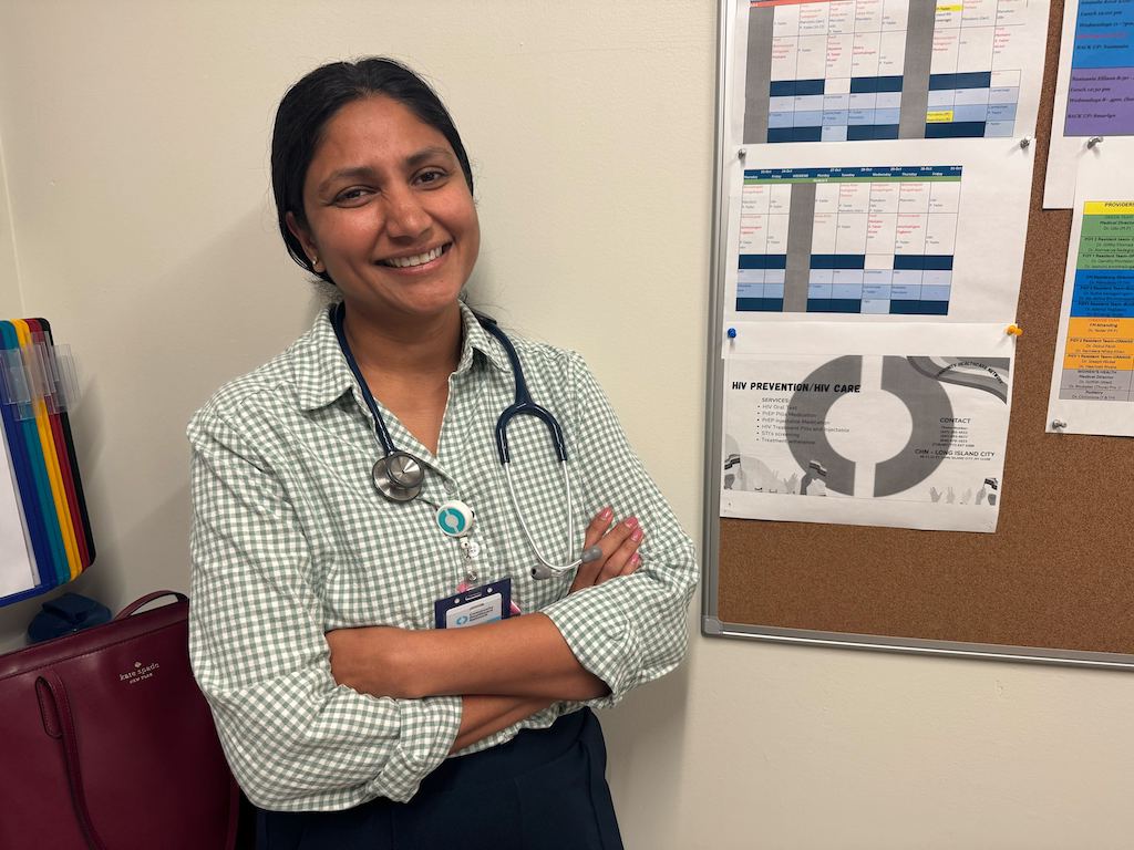 Smiling female doctor with a stethoscope, standing in front of a bulletin boa — Trump Immigration Policies Foreign Doctors