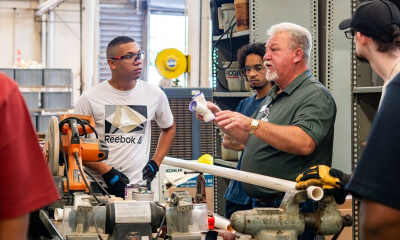 Instructor demonstrates pipe fitting to students in workshop — New Home Construction Decline