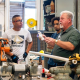 Instructor demonstrates pipe fitting to students in workshop — New Home Construction Decline