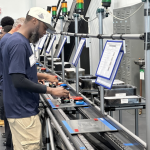 Workers operate equipment on an automotive production line amid discussion of States Losing Jobs and job growth.