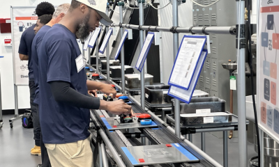 Workers operate equipment on an automotive production line amid discussion of States Losing Jobs and job growth.