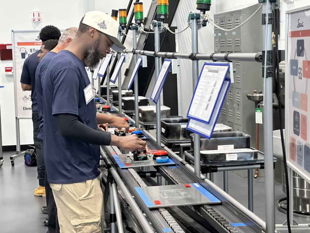 Workers operate equipment on an automotive production line amid discussion of States Losing Jobs and job growth.