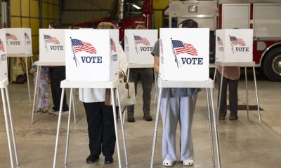 Voters stand at white voting booths with American flag and “I Vote” signs; DOJ Election Subpoenas Los Angeles County i…