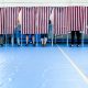 Voters casting ballots behind striped privacy screens in a gymnasium during an election. — Trump voter rolls lawsuit
