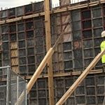 Construction worker in a bright yellow shirt working on a concrete form at a building site — skilled trade worker shortage
