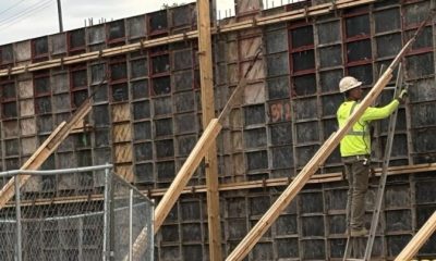Construction worker in a bright yellow shirt working on a concrete form at a building site — skilled trade worker shortage