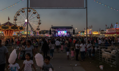 Pensacola Interstate Fair 2026 at dusk, with families walking past a lit Ferris wheel and concert stage.