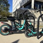 Parked shared electric scooters and bikes outside a city building illustrate e-bike safety laws.