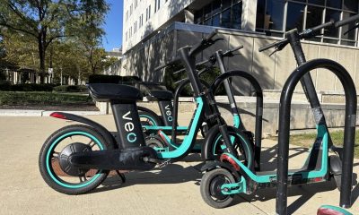 Parked shared electric scooters and bikes outside a city building illustrate e-bike safety laws.