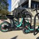 Parked shared electric scooters and bikes outside a city building illustrate e-bike safety laws.