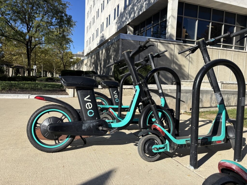 Parked shared electric scooters and bikes outside a city building illustrate e-bike safety laws.