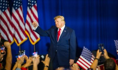 Former President Trump raises his fist in front of a crowd, with America — Federal Election Interference Midterm Elections