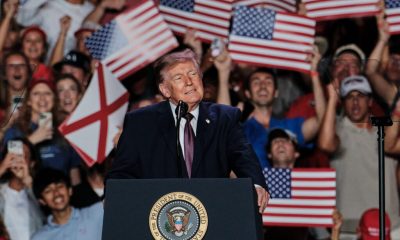 Donald Trump speaking at a rally with supporters holding American flags, promoting mail- — Trump encourages mail-in voting